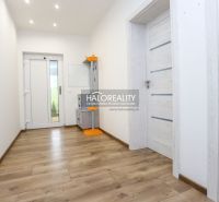 A hallway in a family house with a wooden decor floor and light-colored doors.