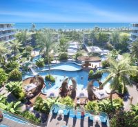 Apartment construction in Phuket with a swimming pool, palm trees, and a sea view.