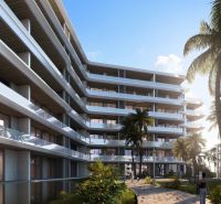 Apartment construction in Phuket with terraced balconies among palm trees and blue skies.