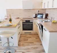 A kitchen in a studio apartment with furnishings and a wooden decor floor.