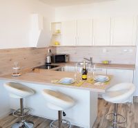 A kitchen with an island, bar stools, and a wood-patterned floor in a studio apartment.