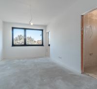 An empty room with a large window in a family house, concrete floor, and incomplete walls.