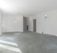 Empty room with white walls and a concrete floor in a family house.