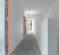A hallway of a family house under renovation with bare walls and ceiling.