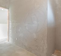 A room in a family house with bare walls and a concrete floor.