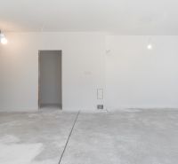 Empty room in a family house with a gray concrete floor and white walls.