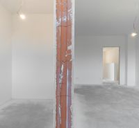 Interior of a family house with an unplastered brick wall and concrete floor in white spaces.