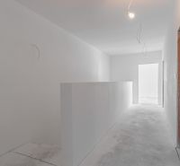 A simple white hallway in a family house with a concrete floor.