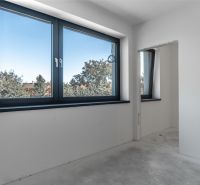 Interior of a family house with white walls and a large window overlooking the trees.