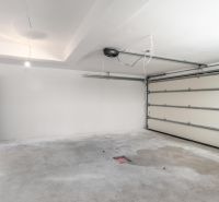 A garage in a family house with a concrete floor and electric doors.