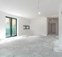A spacious interior of a family house with large windows and a concrete floor.