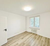 A room in a three-room apartment with a wooden decor floor and a large window.