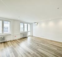 A bright spacious living room with wood-patterned flooring in a 3-room apartment.
