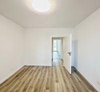 A room with white walls, a wooden decor floor, and open doors in a 3-room apartment.