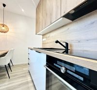 A kitchen in a 3-room apartment with a wooden decor floor and stylish lighting.
