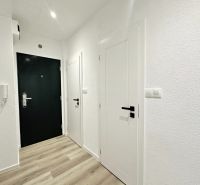 The entrance hall in a 3-room apartment with a wooden decor floor and white walls.