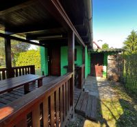 Gardens in Lozorno with a green facade of the cottage and wooden furniture on the terrace.