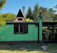 Gardens in Lozorno with a cottage in the forest, green facade, bushy tree, and gazebo.
