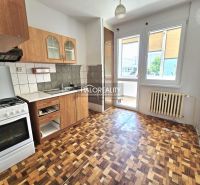 A kitchen in a 3-room apartment with a wooden decor floor and access to a balcony.