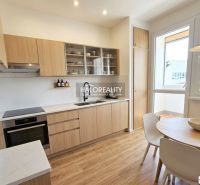 A kitchen in a 3-room apartment with a wooden decor floor and a dining table.
