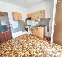 A kitchen in a 3-room apartment with a wooden decor floor and wooden cabinets.