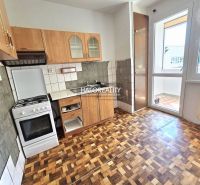 A kitchen with a gas stove and a wooden decor floor in a 3-room apartment.