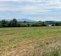 The landscape in Krtovce with residential plots, surrounded by greenery and hills on the horizon.