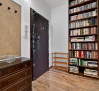 Entrance hallway of a 2-room apartment with bookshelves and a floor with a wood decor.