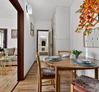 Interior of a 2-room apartment with a dining table, wooden decor flooring, and autumn decorations.