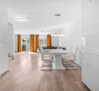 A bright interior of a family house with a kitchen, a wooden decor floor, and orange curtains.