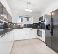 A kitchen in a family house with built-in appliances and glossy white cabinets.
