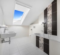 A bathroom in a family house with a large skylight and elegant tiles.