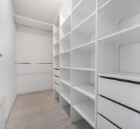 A wardrobe with numerous shelves and drawers in a family house with a wooden decor floor.