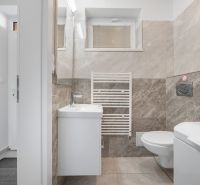 A bathroom with beige tiles and white accessories in a family house.