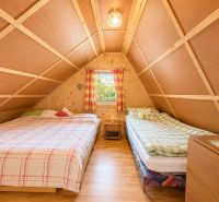 Attic bedroom with two beds, wooden decor, and a window in a cabin.