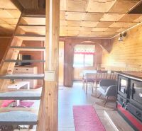 Interior of a cabin with wooden paneling, a kitchenette, and a staircase. Floor with a wood decor.