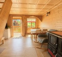 Wooden interior of a cabin with a kitchenette and a sofa, floor with wooden decor.