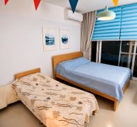 A bedroom in a one-room apartment with two beds and colorful blinds.