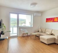 Living room with a sofa, armchair, table, and wooden decor flooring in a 2-room apartment.