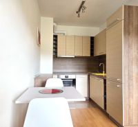 A kitchen in a 2-room apartment with a wood-patterned floor and a white table.