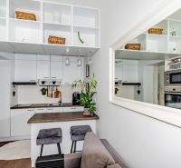 The kitchen in a 2-room apartment with white cabinets and a mirror, wood-effect flooring.