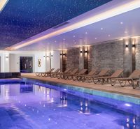 An indoor pool with loungers and a starry effect on the ceiling in a studio apartment.