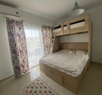 A bedroom in a studio apartment with a bunk bed, curtains, and a balcony.