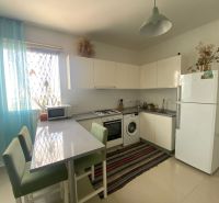 Kitchen in a studio apartment, white furniture, stove, refrigerator, washing machine, dining counter.