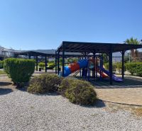 A children's playground in Tatlisu surrounded by greenery and walkways near 2-bedroom apartments.