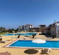 Exterior of the complex in Tatlisu with pools and sunbeds, ideal for a 2-bedroom apartment.