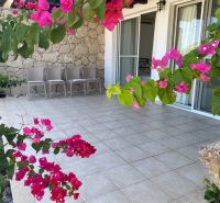 Terrace of a 2-bedroom apartment in Tatlisu with garden furniture and bougainvillea flowers.