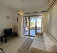 Living room of a two-room apartment with a white sofa and a TV stand.