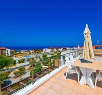 A rooftop terrace with a sea view in Tatlisu, surrounded by green gardens and a swimming pool.