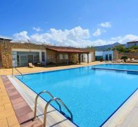 Exterior of a 2-bedroom apartment in Tatlisu with a sunken pool and loungers.